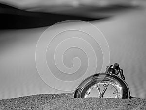 Pocket watch buried into the desert sand