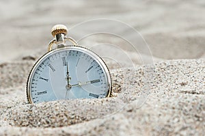 Pocket watch buried in sand.