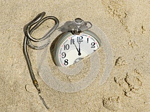 Pocket watch buried in sand.