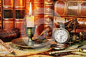 Pocket watch, burning candle and old books