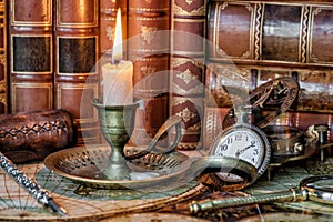 Pocket watch, burning candle and old books