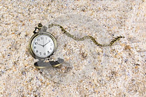 Pocket watch with chain in the sand. Time passing symbol