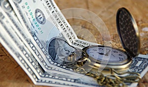 Pocket watch with dollars on wooden trunk