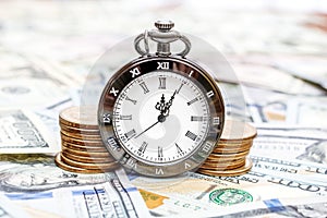Pocket watch with golden coins on the background of dollar bills. Business concept