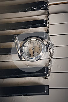 Pocket watch on old keyboard piano