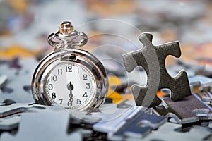 Pocket watch on a pile of jigsaw puzzle pieces