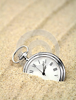 Pocket watch semi buried in the sand