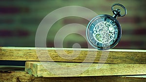 Pocket watch on stacked lumber in morning.