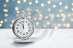 Pocket watch on table against blurred lights. Christmas countdown