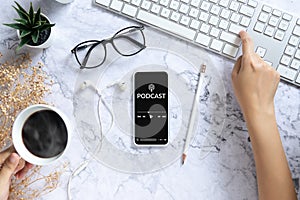 Podcast audio content concept. podcast application on mobile smartphone screen on workspace desk with coffee cup, earphones