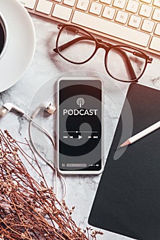 podcast audio content concept. podcast application on mobile smartphone screen on workspace desk with coffee cup, earphones