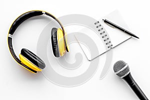 Podcast record with notebook, microphone and headphones on white background top view space for text