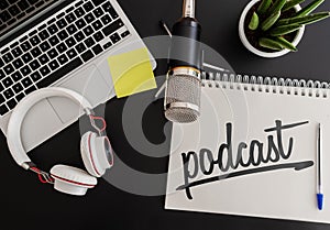 Podcast recording concept with microphone, headphones and laptop computer next to note pad