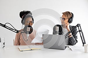 Podcasters, African American and European woman with headphones and microphone