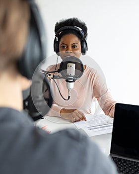 Podcasters, African American and European woman with headphones and microphone