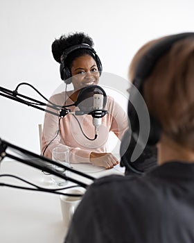 Podcasters, African American and European woman with headphones and microphone
