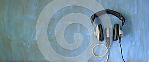 Podcasting concept, vintage headphones and recording microphone on grungy blue background