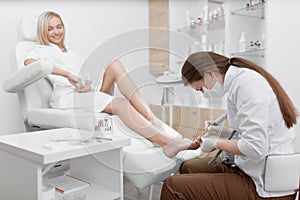 Podiatrist making procedure for smiling clients foot.