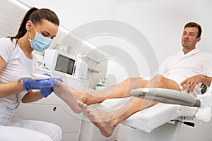 Podiatrist peeling feet with special electric device