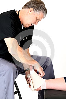 Podiatrist in scrubs wrapping a girls ankle