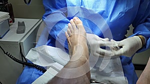 Podiatrist in white gloves clean with cotton a toenail. Concept of podology and chiropody.