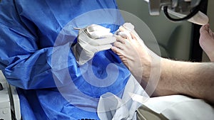 Podiatrist in white gloves clean with cotton a toenail. Concept of podology and chiropody.