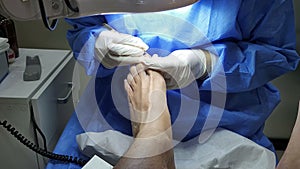 Podiatrist in white gloves clean with cotton a toenail. Concept of podology and chiropody.