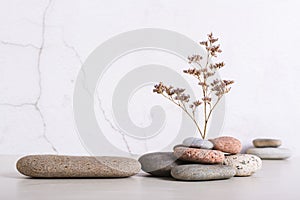 A podium made of smooth sea stone and a dried flower from a pile of stones on the table