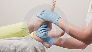 Podologist in blue medical gloves massages a female flat foot. Closeup. Slow motion. Concept of chiropody, podology and