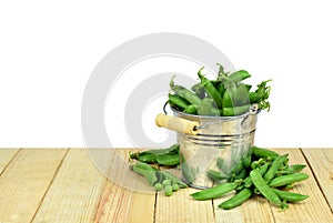 Pods of green peas in a bucket. Isolated.