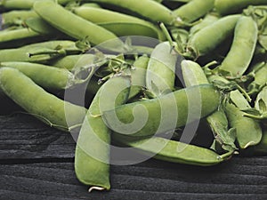 Pods of green peas on a old wooden surface close up