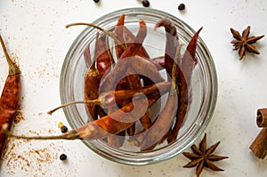 pods of red hot pepper in a jar on a white background