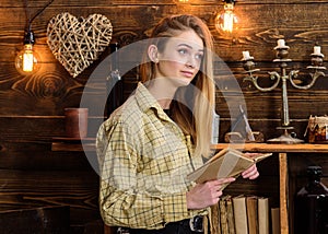 Poetry evening concept. Girl reading poetry in warm atmosphere. Lady on dreamy face in plaid clothes holds book, reading photo