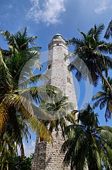 Point Dondra, Lighthouse in Dondra, Sri Lanka. Palm trees and a blue sky.