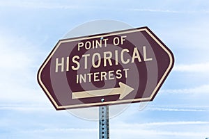 Point of Historical Interest road sign with an arrow against blue sky