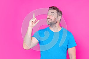 The point up. Look up. Happy handsome man pointing up away, isolated pink background. Excited man pointing a great idea