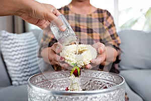 Point of view of child pouring water on hands of elder senior or respected grandparents