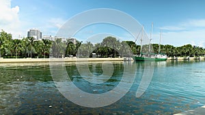 Point of view footage along a footpath at Maurice A. Ferre Park with blue ocean water, a ship docked, lush green palm trees and