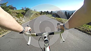Point of view. Male road cyclist riding his bicycle downhill on a asphalt road on a sunny day