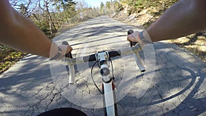 Point of view. Male road cyclist riding his bicycle uphill on a sunny day