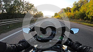 Point of view of motorcyclist driving motorbike at highway with sun flares. The viewpoint of motorcycle rider rides in