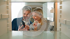 Point of view POV inside refrigerator Caucasian adult family mature couple middle-aged man woman open empty fridge order