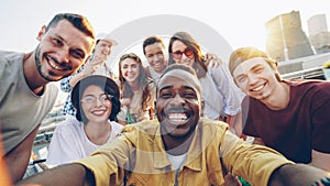 Point of view shot of young people multiethnic group taking selfie and holding camera, men and women are looking at