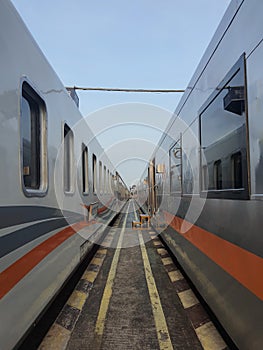 Point of view standing between two trains at a train station