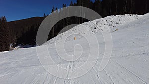 Point of view video clip of person skiing under chair lift on a piste going through the trees on a mountain with a blue sky