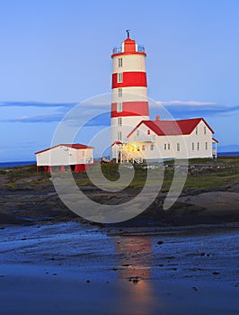 Pointe-des-Monts Lighthouse at dusk with reflections in the sea, Cote-Nord, Quebec photo