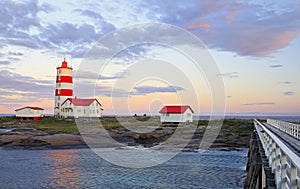 Pointe-des-Monts Lighthouse at sunset with reflections in the sea, Cote-Nord, Quebec