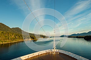 Pointed bow of cruise ship , southbound on ocean channel, Alaska Inside Passage, in warm afternoon sun.