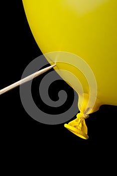 A pointed stick ready to pop a yellow balloon