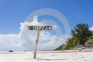 Pointer pizza on a wooden post on the tropical sand beach of Zanzibar island, Tanzania, Africa. Travel and vacation concept
